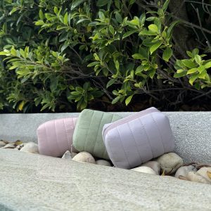 Three allour pouches resting on a stone ledge by a garden