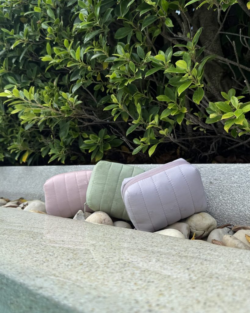 Three allour pouches resting on a stone ledge by a garden