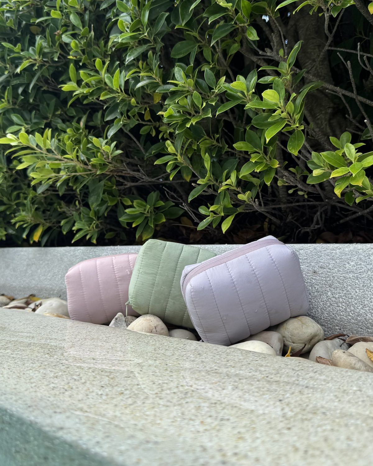 Three allour pouches resting on a stone ledge by a garden